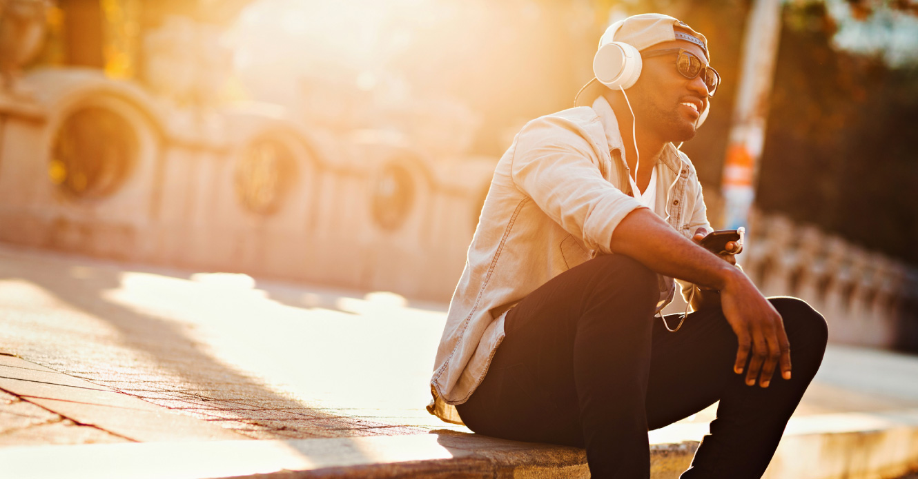 A man on his phone sitting on the sidewalk.