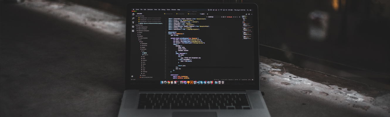 Photo of laptop in a dark room with data coding on screen