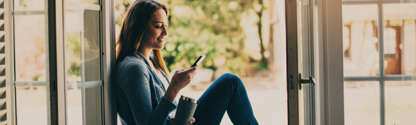 A woman sitting in a doorway on her mobile phone.