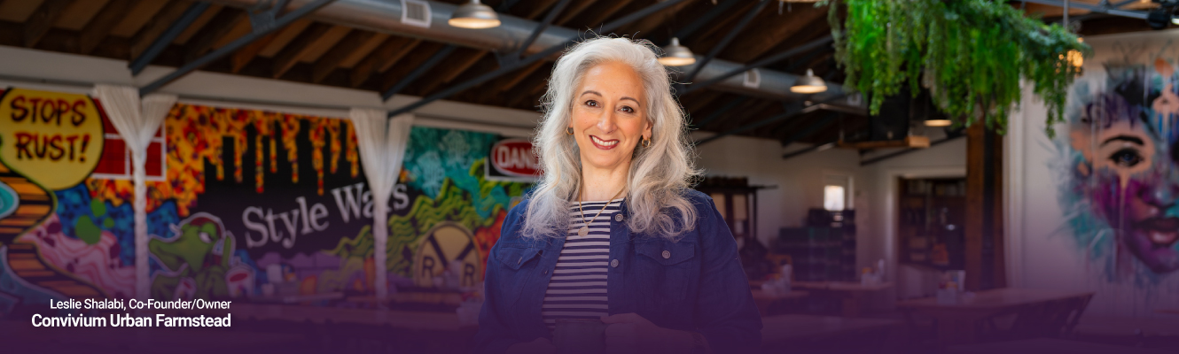 Leslie Shalabi standing in front of artistic murals at Convivium
