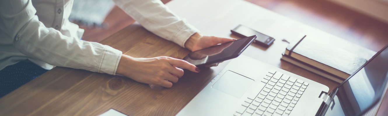 Person looking at a tablet and computer screen ready to open online account in the comfort of their own space.