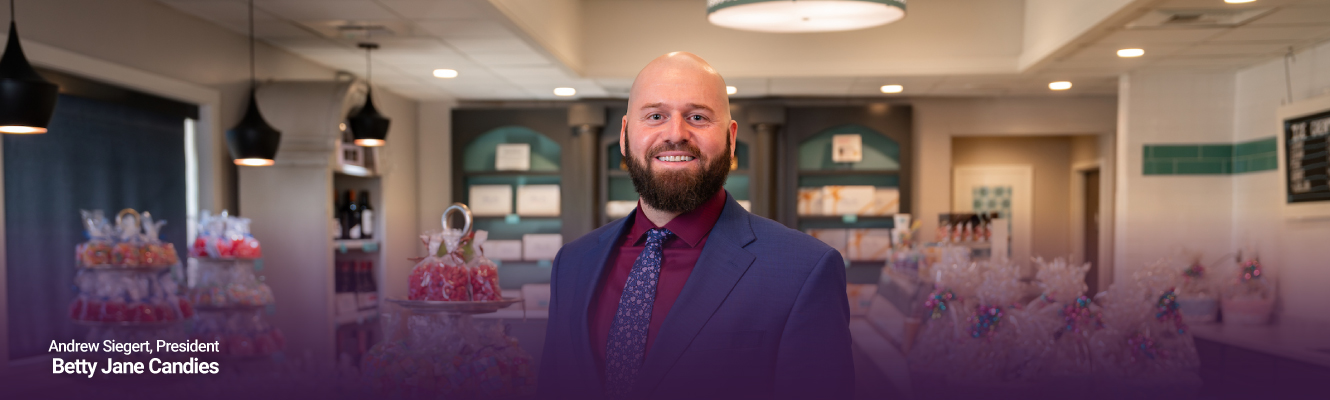 Andrew Siegert of Betty Jane Candies standing in his retail store in front of assorted candies and chocolates