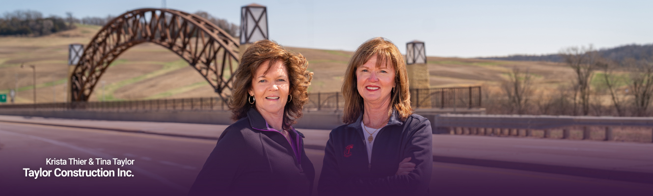 Krista Thier and Tina Taylor of Taylor Construction standing in front of bridge built by the company.